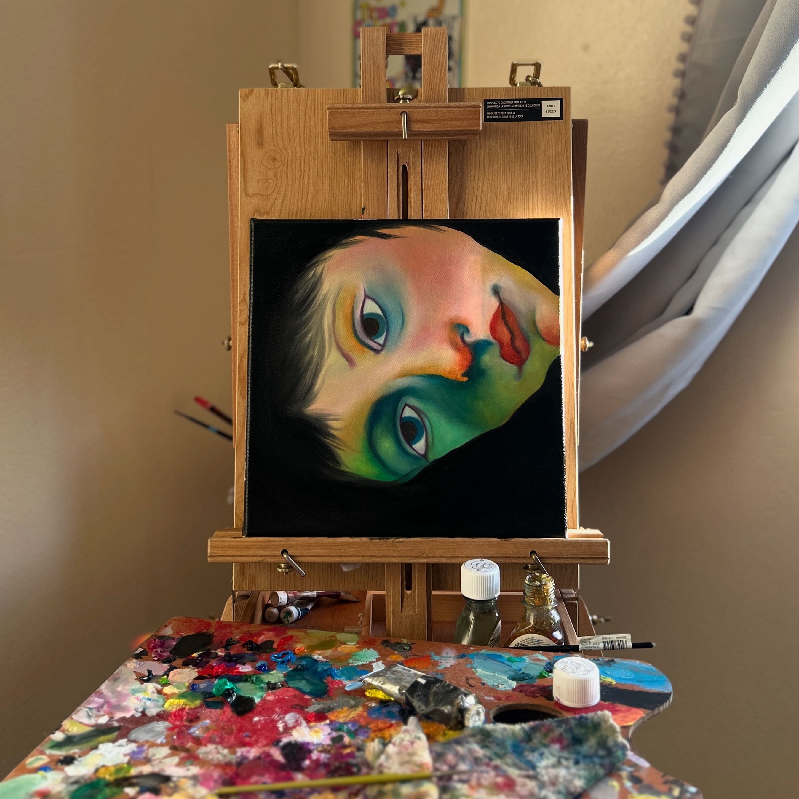 Colorful portrait on an easel beside a paint palette